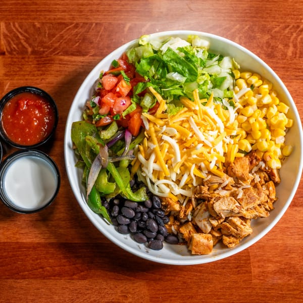 Overhead view of a colorful Al Tacos Locos burrito bowl with chicken, corn, beans, and vegetables.