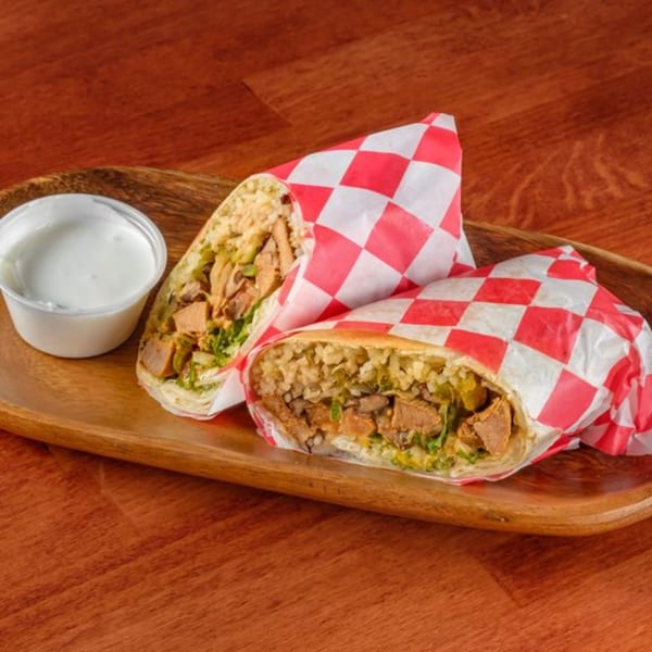 Two Al Tacos Locos burritos, wrapped in red and white checkered paper, with a side of sour cream.